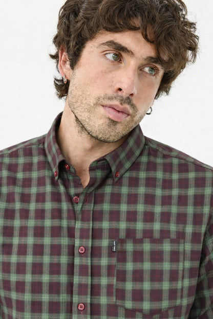 Man wearing a green and red plaid shirt against a white background