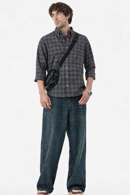 Man wearing a plaid shirt and jeans with a black bag over one shoulder on a white background