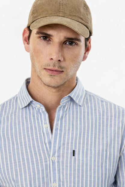 Man wearing a beige cap and light blue striped shirt on a white background