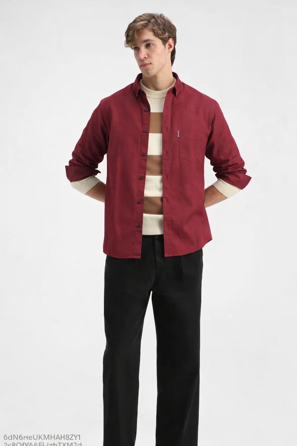 Man wearing a red shirt over a white sweater with black pants on a white background