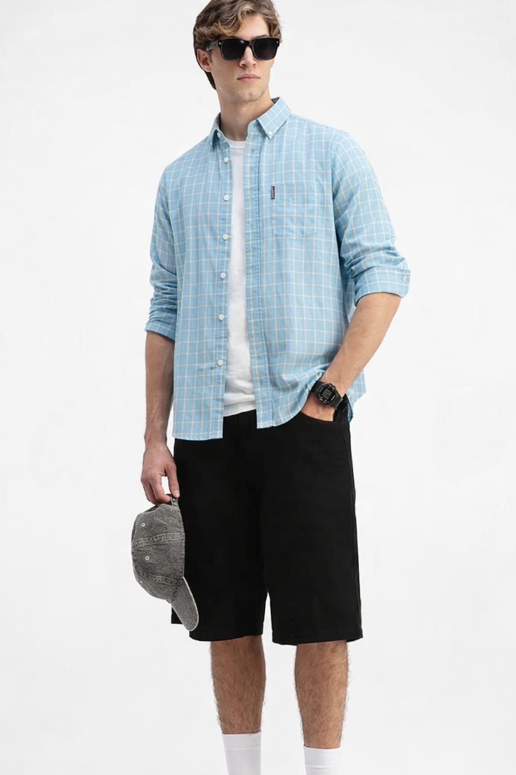 Man wearing a light blue checkered shirt, black shorts, and sunglasses on a white background