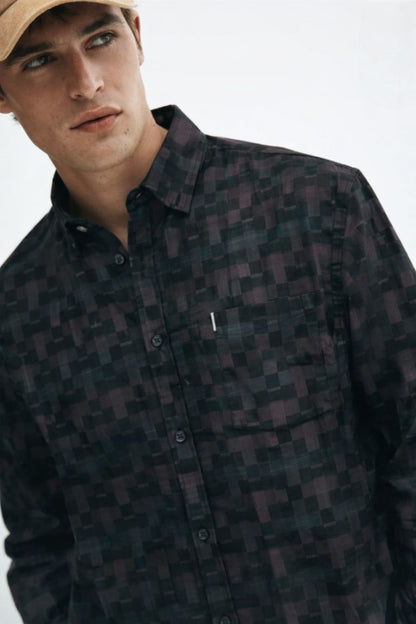 Man wearing a dark patterned shirt and beige cap on a white background