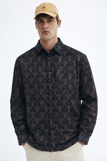 Man wearing a patterned shirt and beige cap on a white background