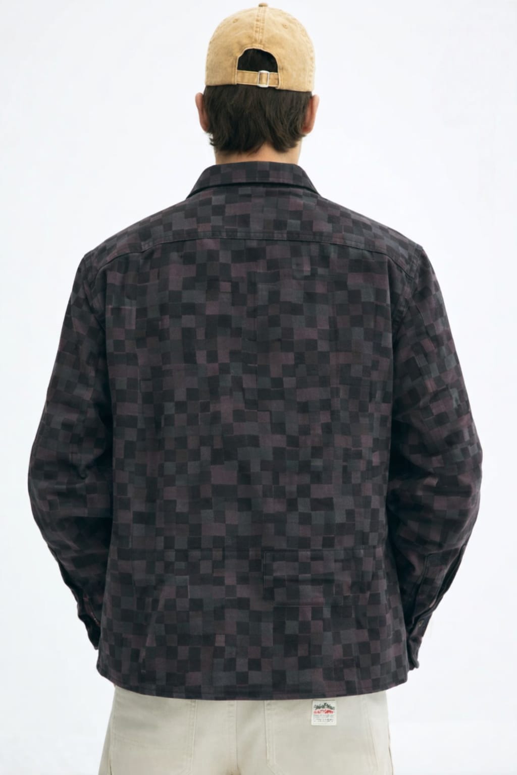 Person wearing a patterned jacket and beige cap on a white background