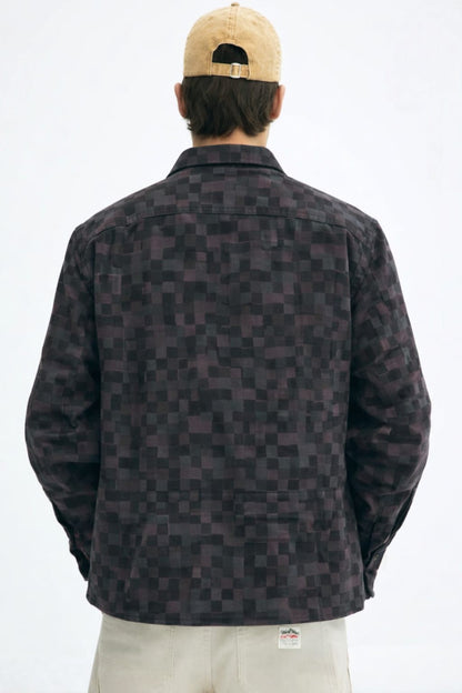 Person wearing a patterned jacket and beige cap on a white background