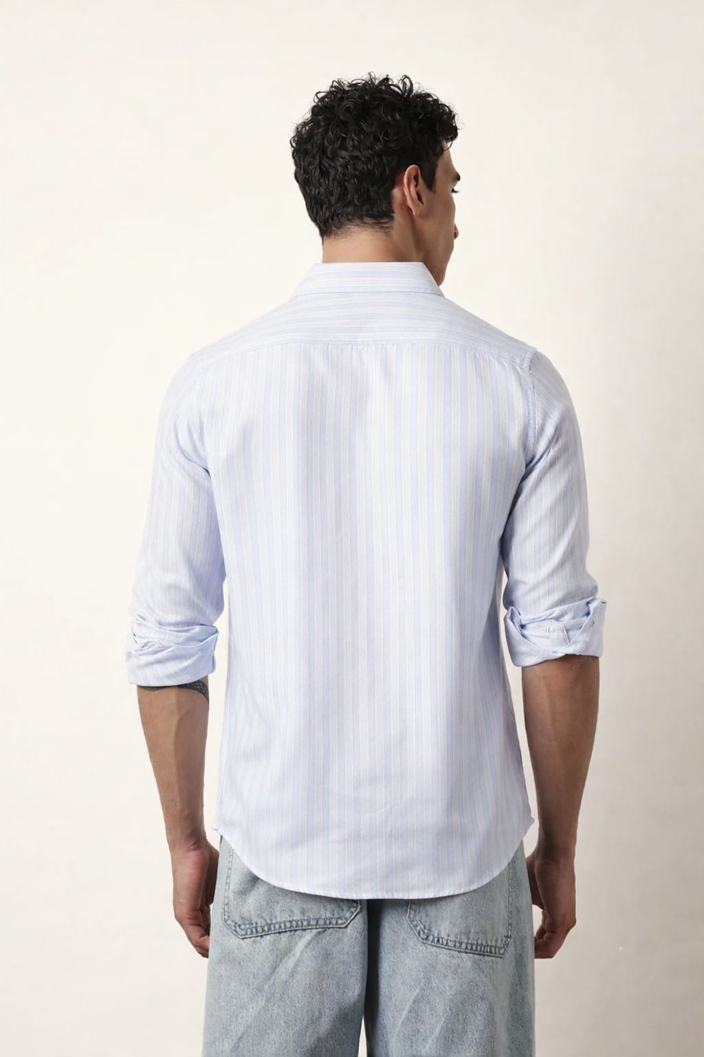 Man wearing a light blue striped shirt and light gray pants against a white background