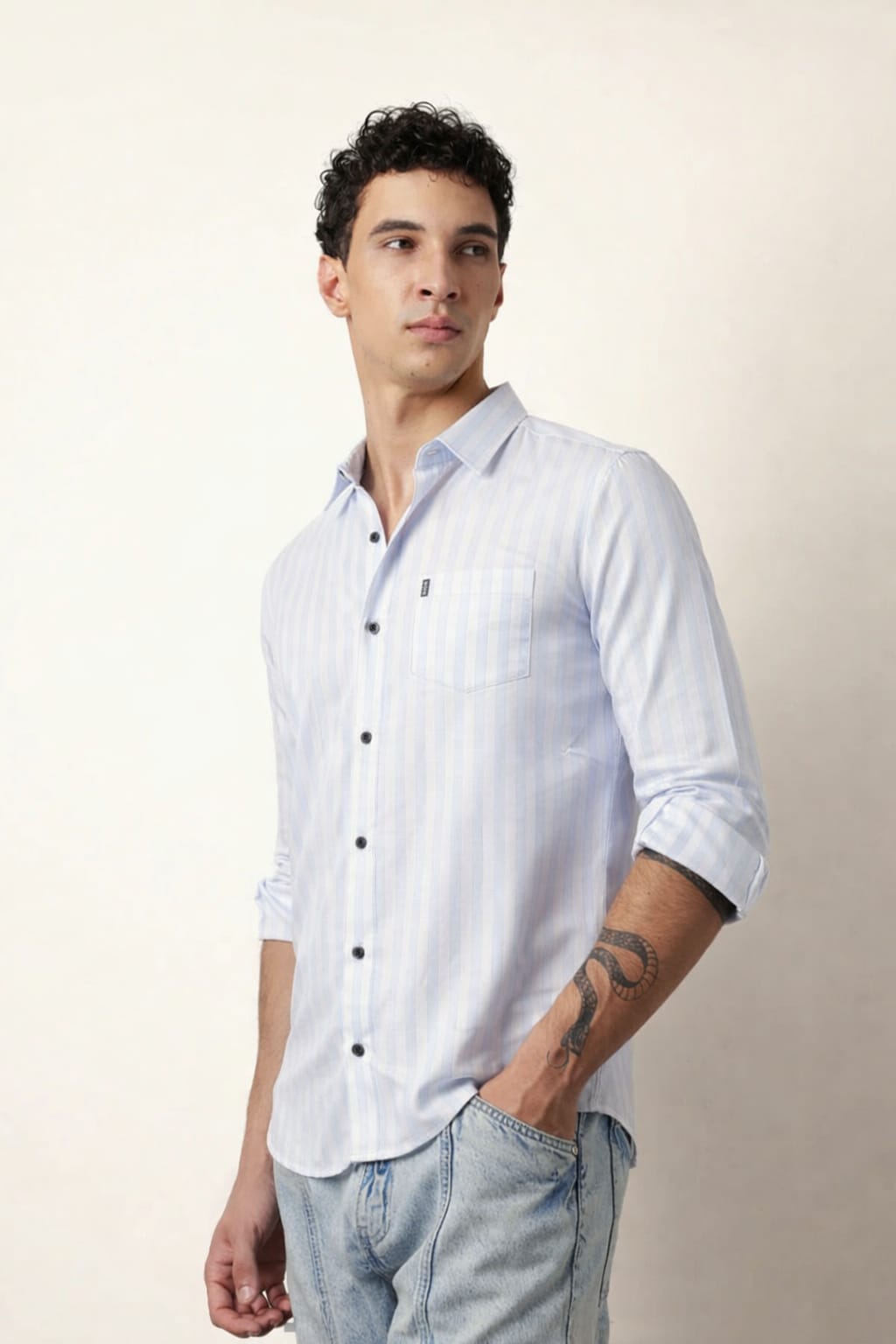 Man wearing a light blue button-up shirt and jeans against a plain background