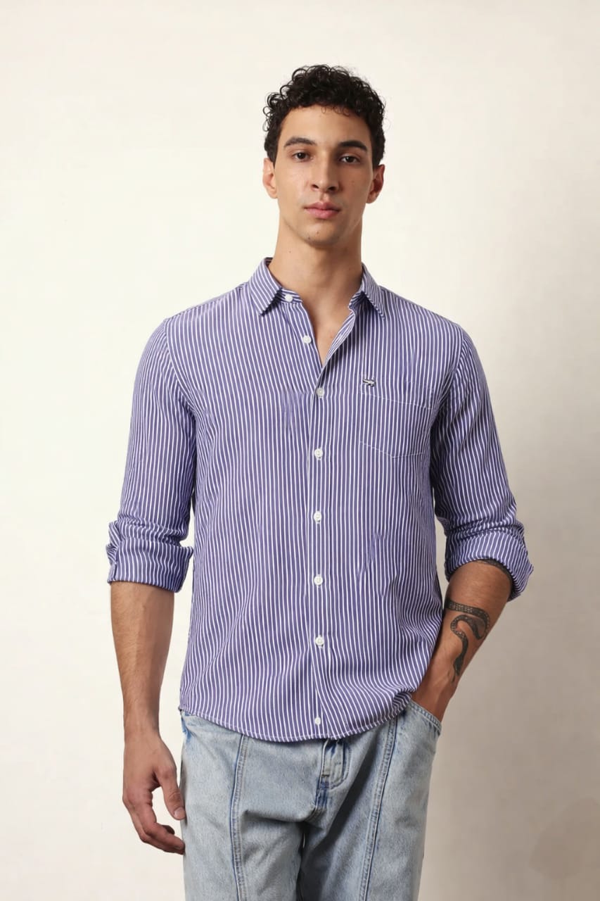 Man wearing a purple striped shirt and light blue jeans against a plain background