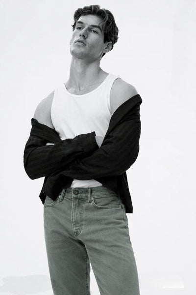 Man wearing a black and white outfit with light-colored pants on a plain background