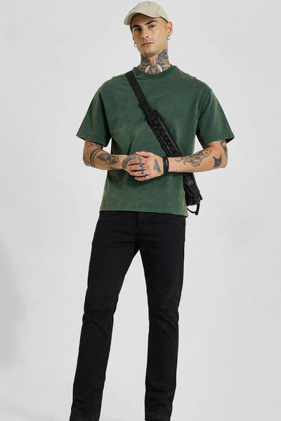 Man wearing a green t-shirt and black pants with a white background