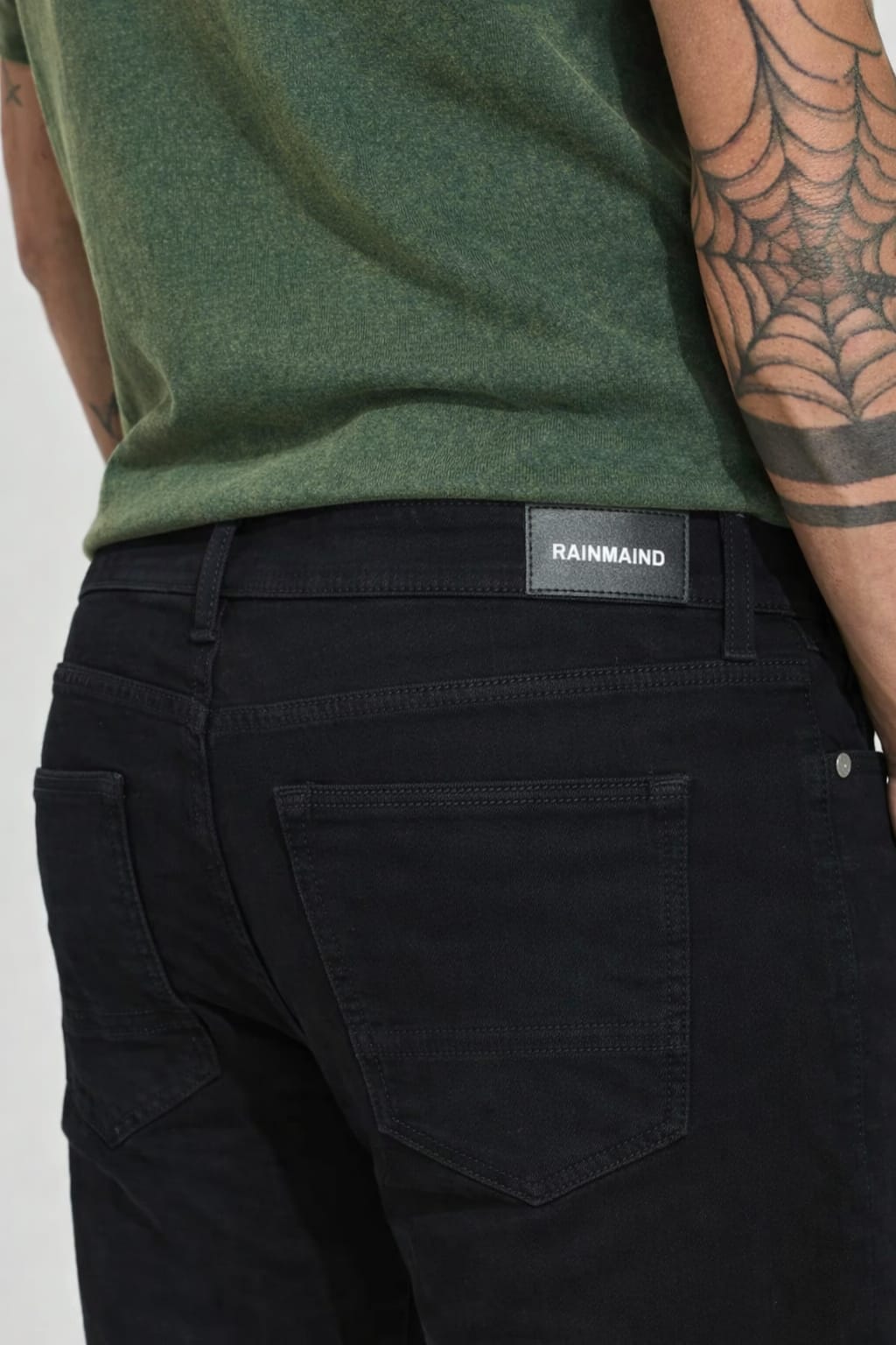 Person wearing black pants with a visible brand label on a white background