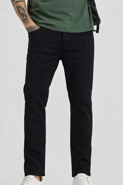 Person wearing black pants and a green shirt on a plain background
