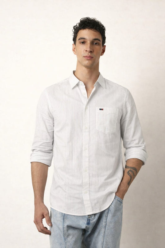 Man wearing a white button-up shirt with a small logo on a plain background