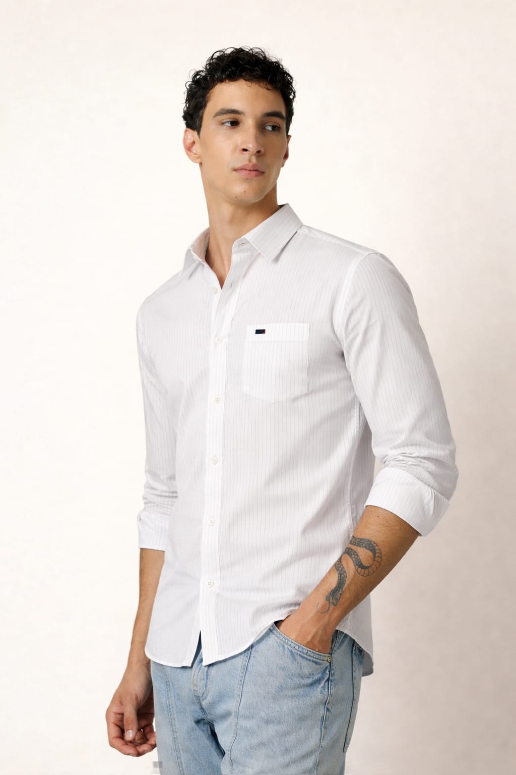 Man wearing a white shirt with a brand logo on a plain background