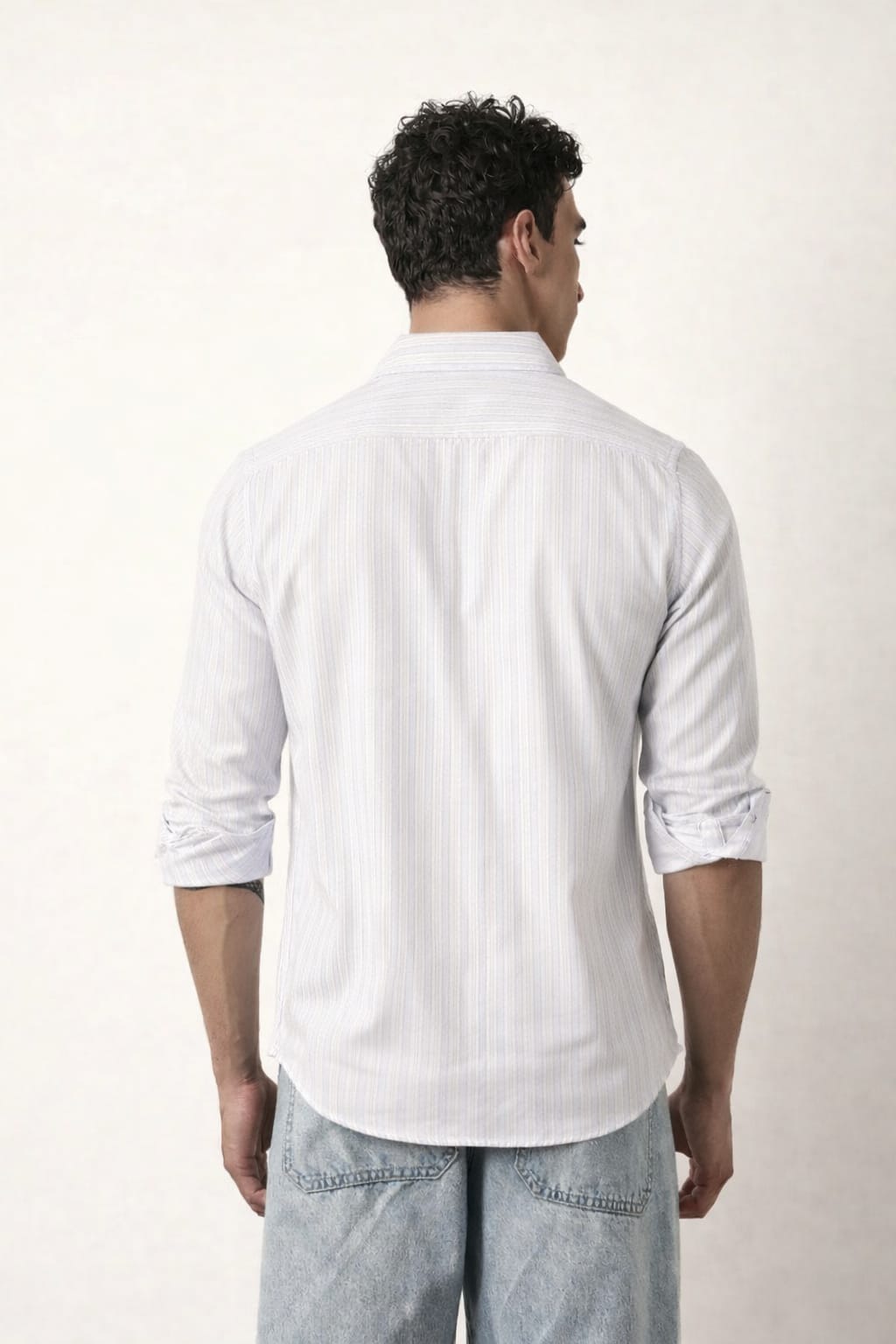 Man wearing a white shirt and light blue jeans on a plain background