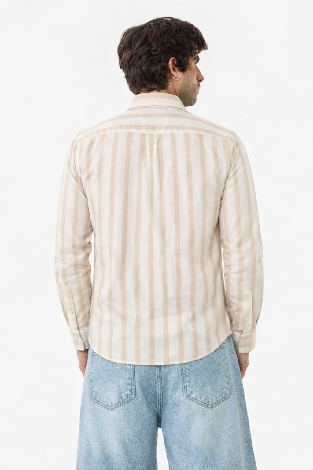 Man wearing a beige and white striped shirt and light blue jeans on a white background