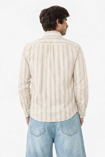 Man wearing a beige and white striped shirt and light blue jeans on a white background