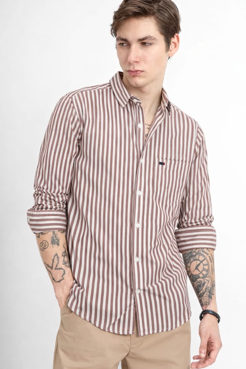 Man wearing a striped shirt with rolled-up sleeves on a white background