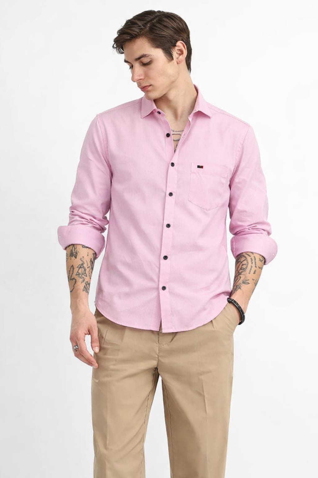 Man wearing a pink shirt and beige pants on a white background