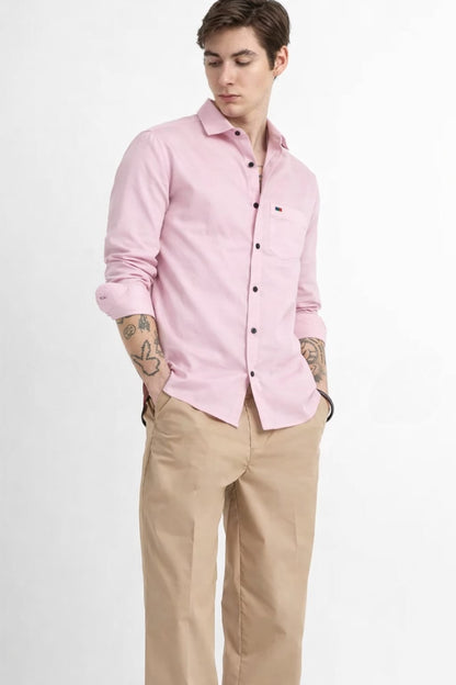 Man wearing a pink shirt and beige pants on a white background