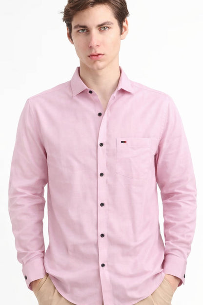 Man wearing a pink button-up shirt with a brand logo on a white background