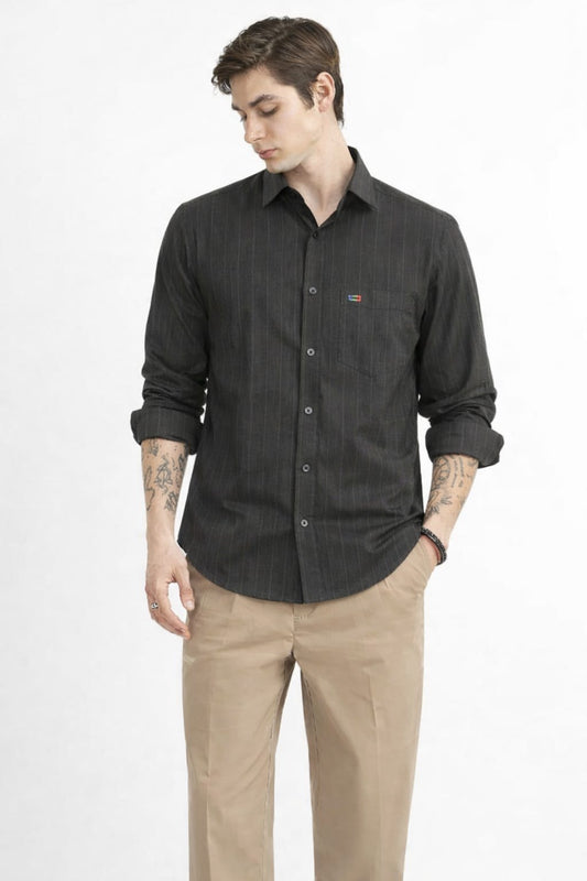 Man wearing a dark gray button-up shirt and beige pants on a white background