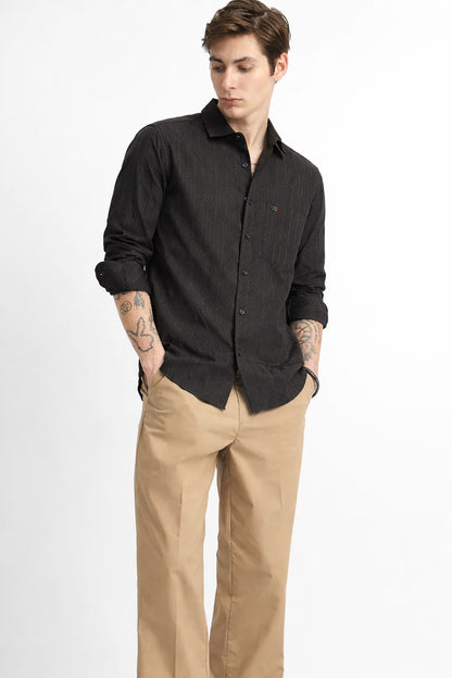 Man wearing a black shirt and beige pants on a white background