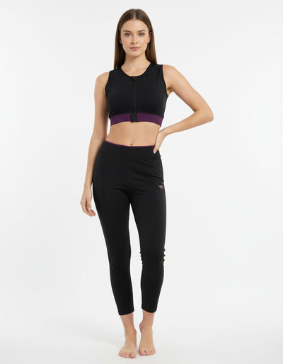 Woman wearing a black athletic outfit with a purple accent on a white background