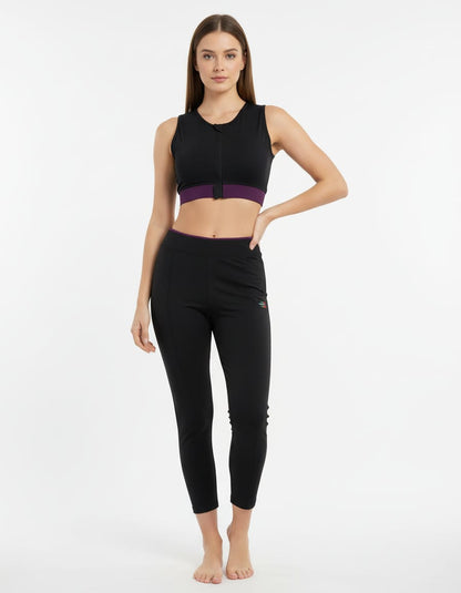 Woman wearing a black athletic outfit with a purple accent on a white background