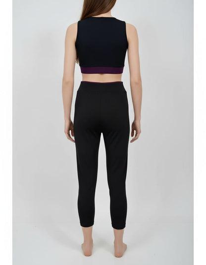 Person wearing a black sports bra and leggings set on a white background