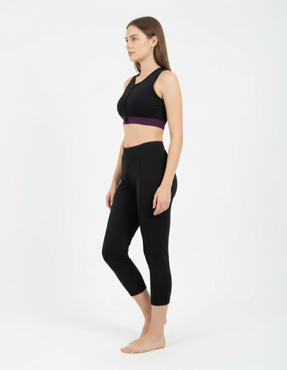 Woman wearing a black athletic outfit with a purple band on a white background