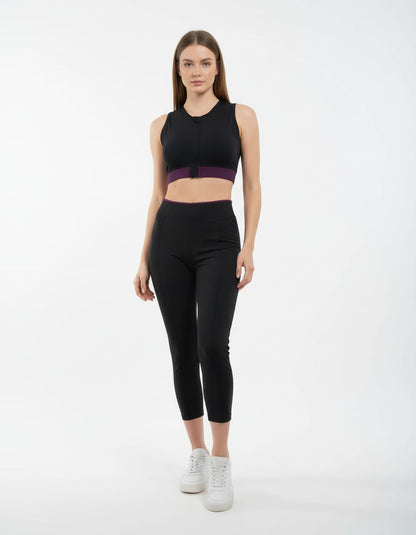 Woman wearing a black athletic outfit with a purple accent on a white background