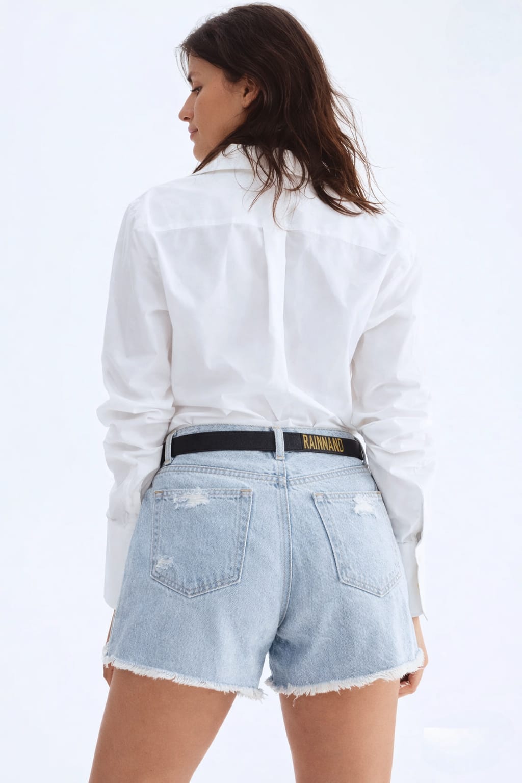 Person wearing a white shirt and light blue denim shorts on a white background