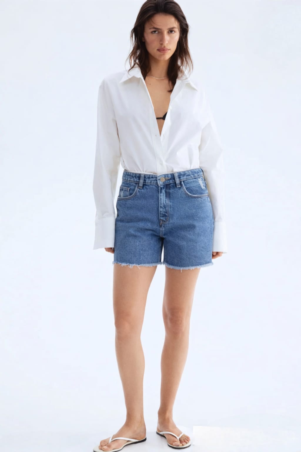 Woman wearing a white blouse and blue denim shorts on a white background