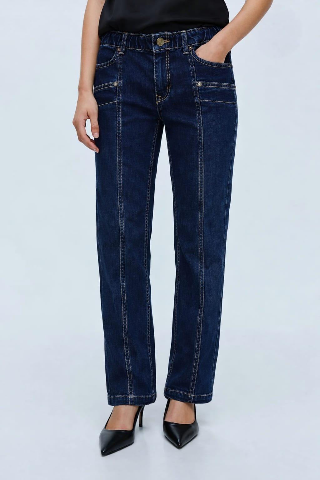 Person wearing dark blue jeans on a light gray background