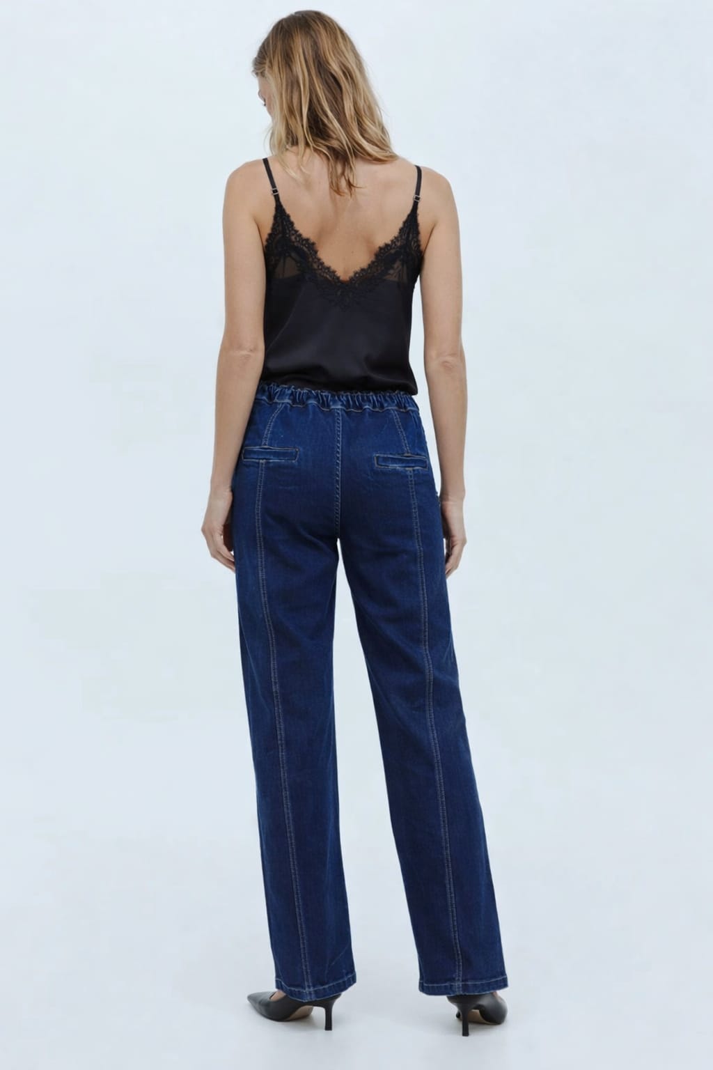 Woman wearing a black lace top and blue jeans on a white background