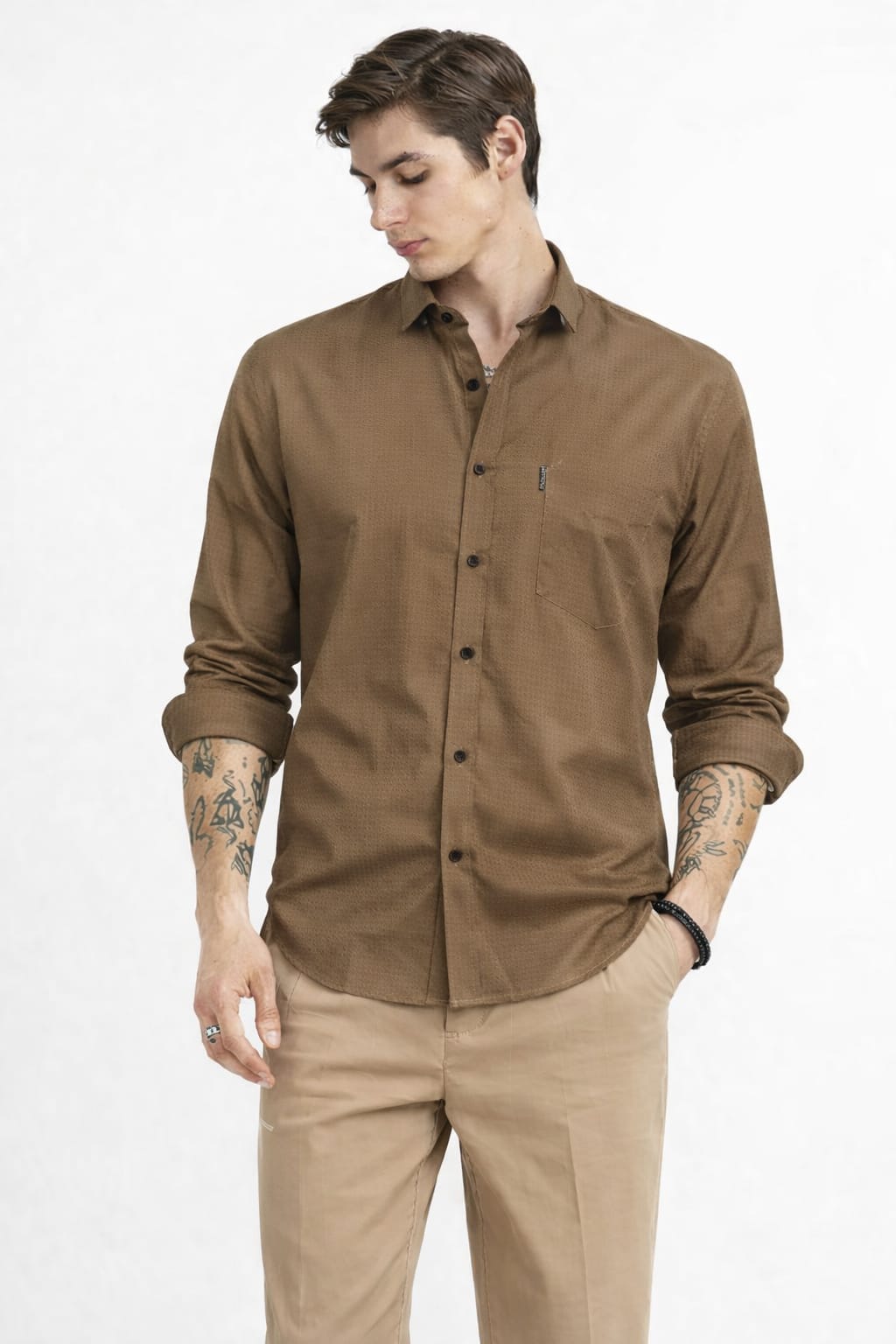 Man wearing a brown button-up shirt and beige pants on a white background