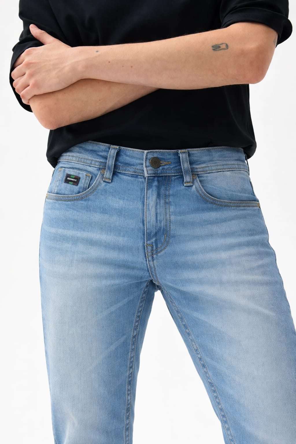 Person wearing light blue jeans and a black shirt on a white background