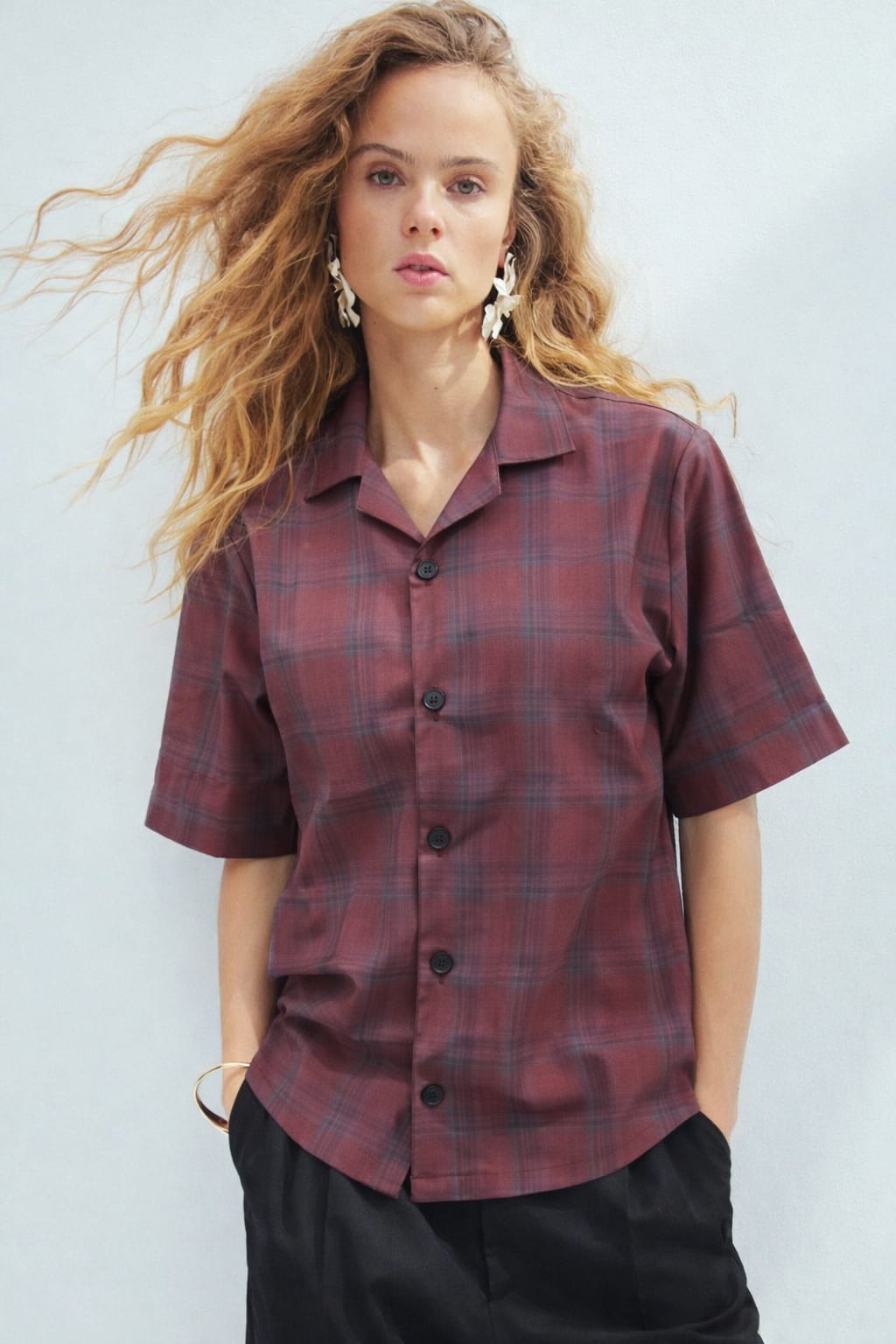 Woman wearing a plaid shirt against a plain background