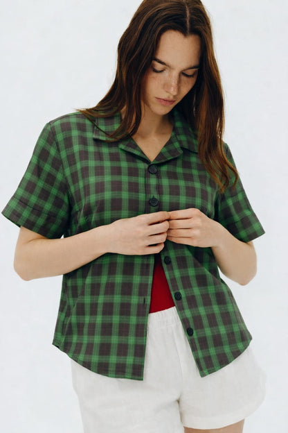 Woman wearing a green plaid shirt and white shorts on a white background