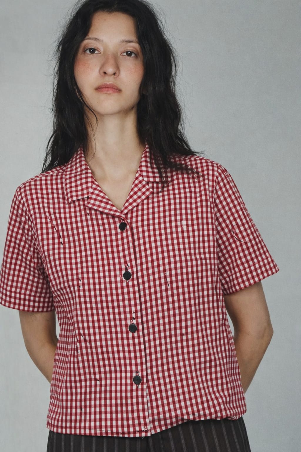 Person wearing a red and white checkered shirt against a gray background