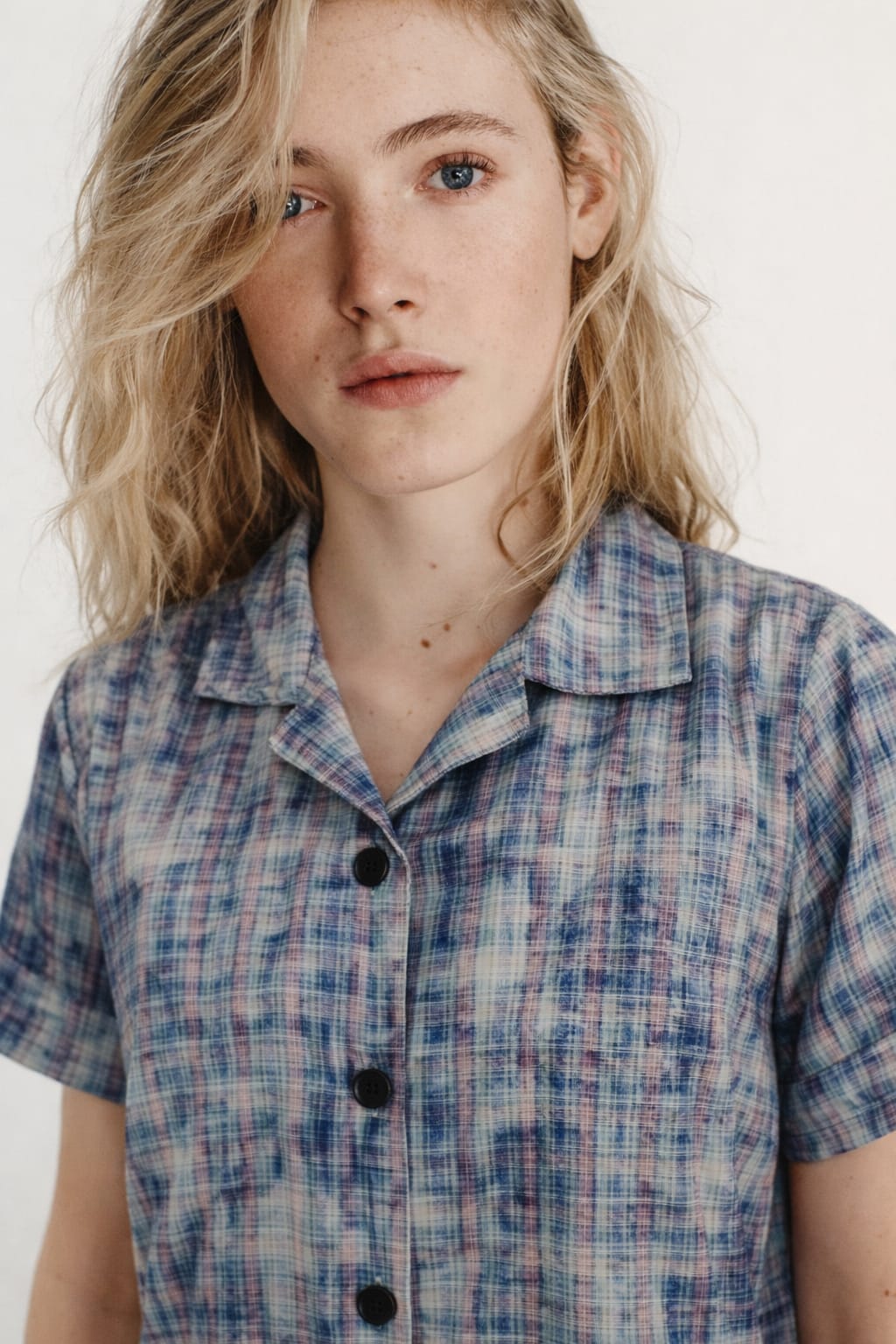 Woman wearing a plaid shirt with a plain background