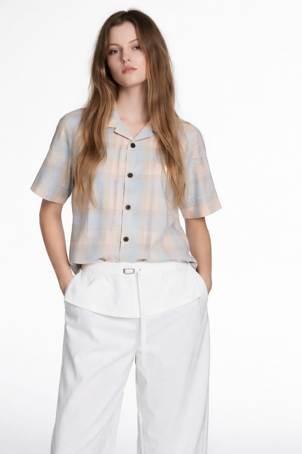 Woman wearing a plaid shirt and white pants on a white background