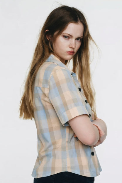Woman wearing a plaid shirt with black buttons on a white background