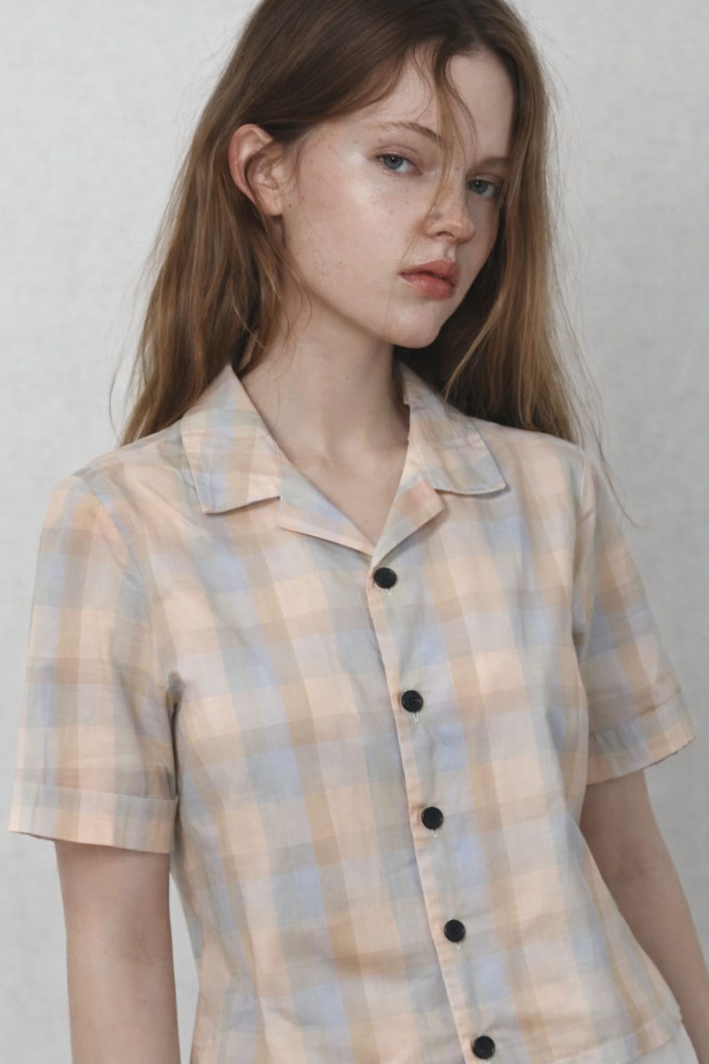 Woman wearing a plaid shirt against a plain background