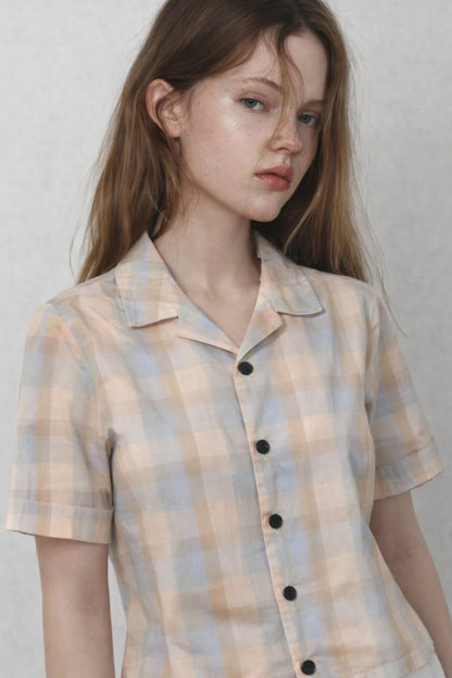 Woman wearing a plaid shirt against a plain background