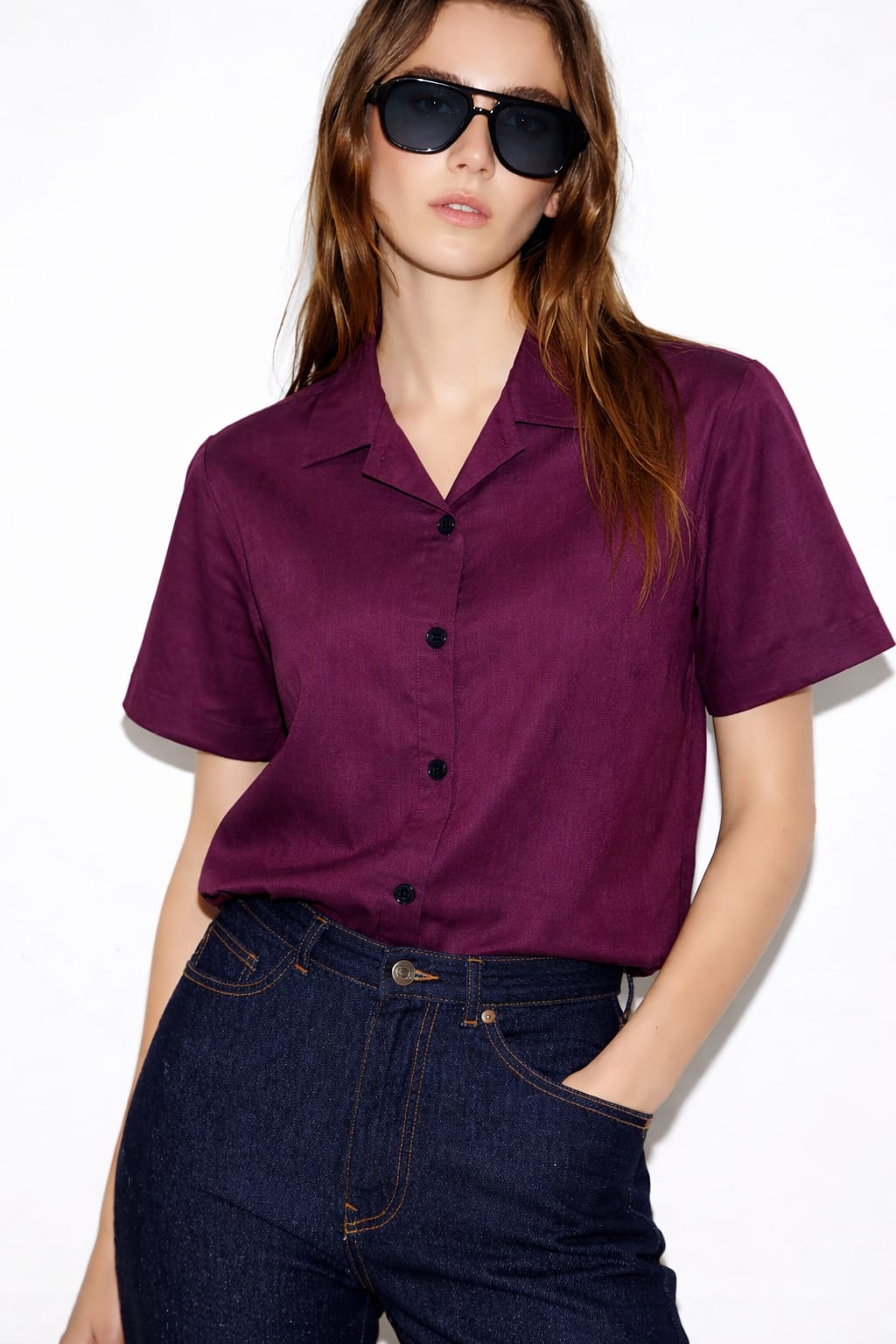 Woman wearing a purple shirt and sunglasses on a white background