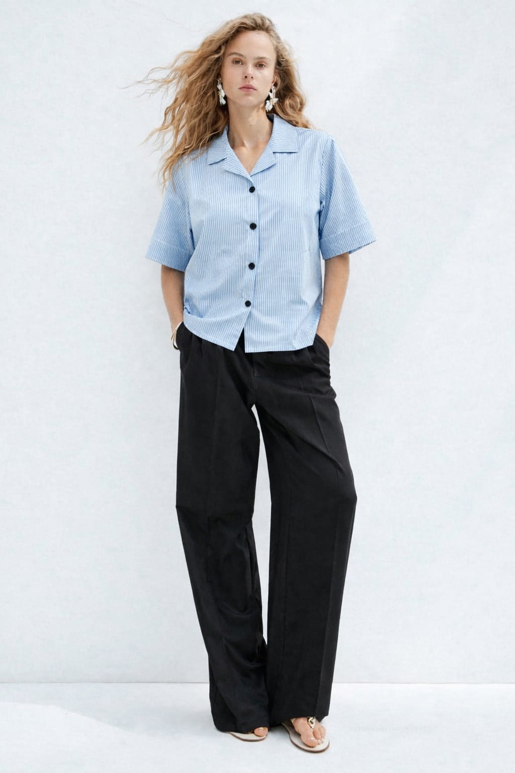 Woman wearing a light blue shirt and black pants on a white background
