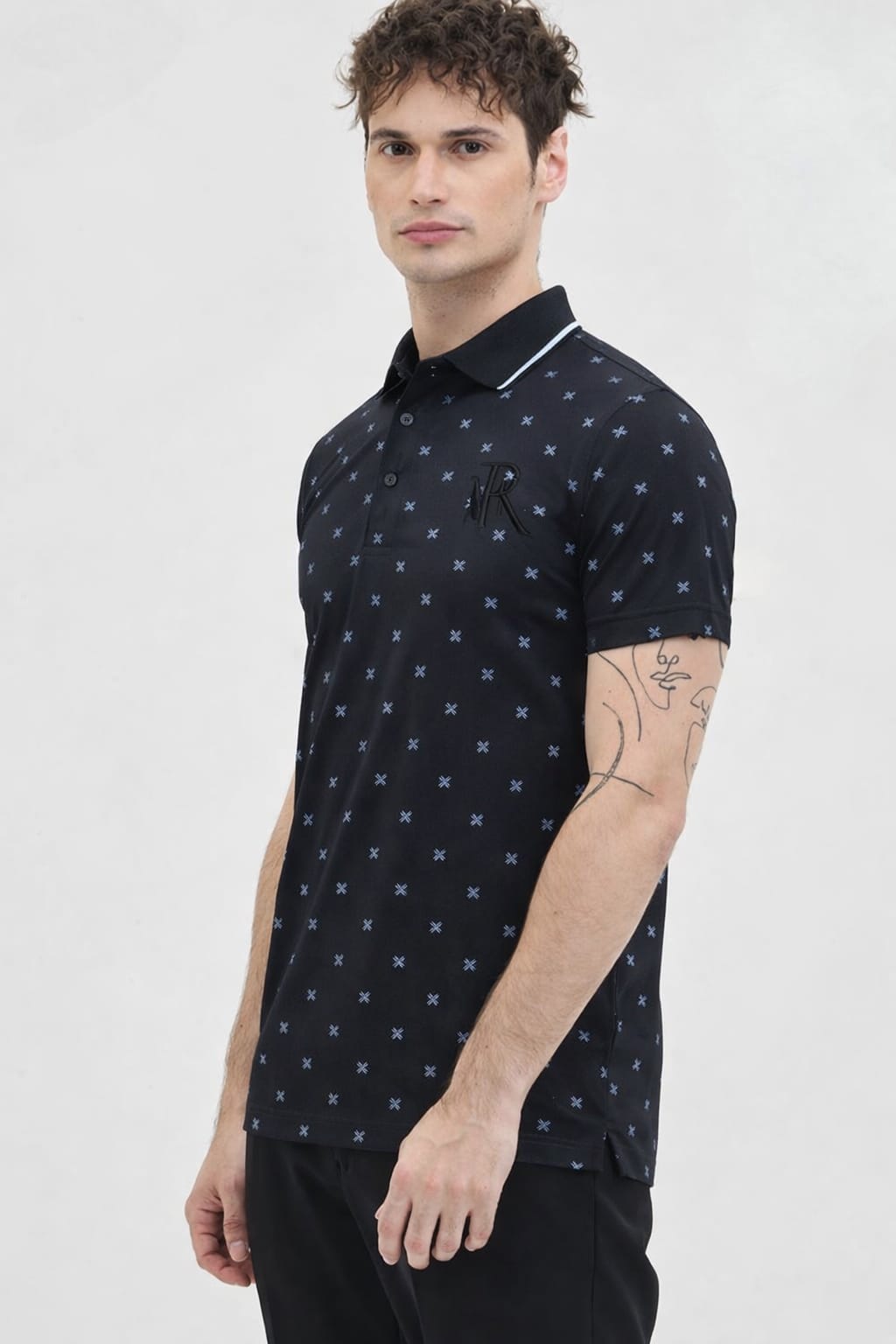 Man wearing a black polo shirt with white star pattern on a white background