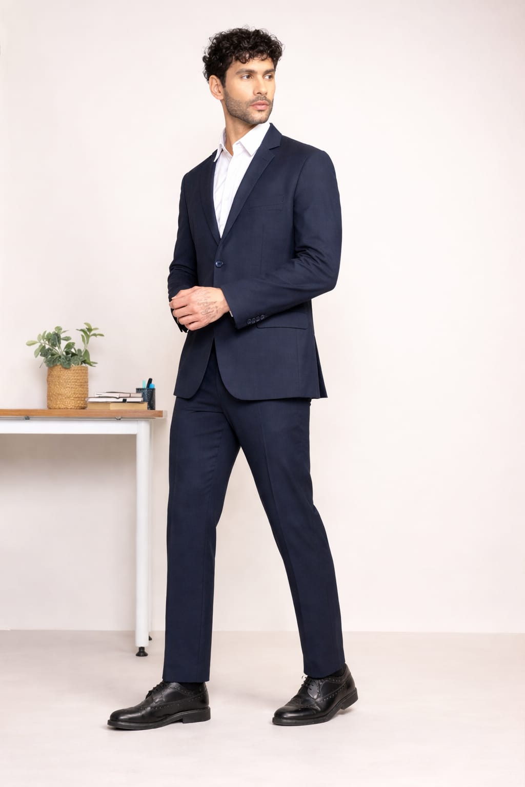 Man wearing a navy suit with a white shirt in an indoor setting.